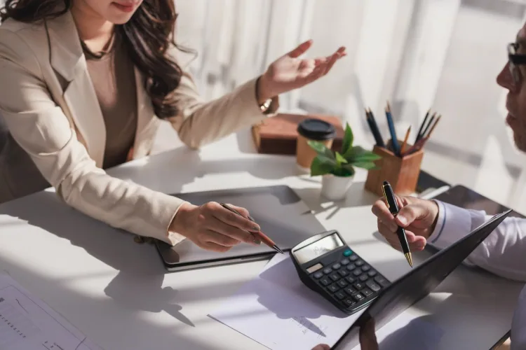 Loan officer using a calculator to review a self-employed borrower’s bank statement cash flow